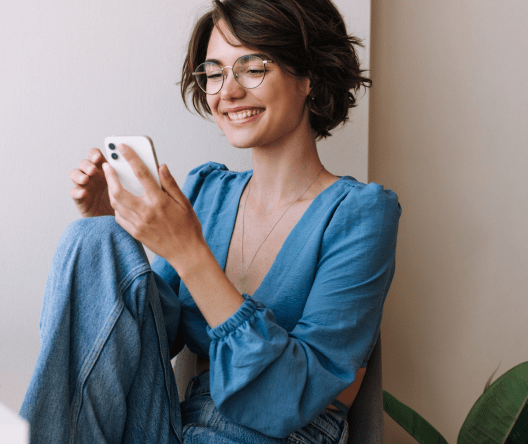 Smiling girl looking at her mobile phone while using it